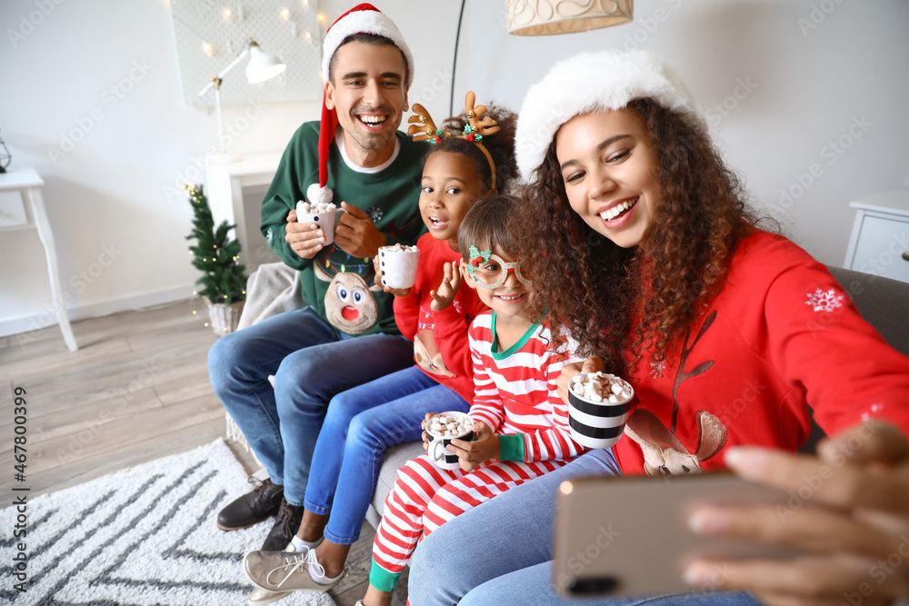 Happy family with cups of hot cocoa taking selfie at home on Christmas eve Happy family with cups of hot cocoa taking selfie at home on Christmas eve