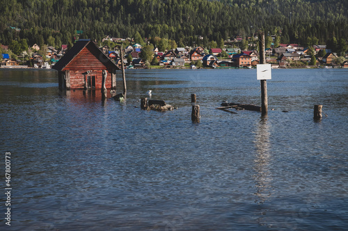 summer vacation in the mountains. spring flood on the lake. a flooded pier and a wooden house.