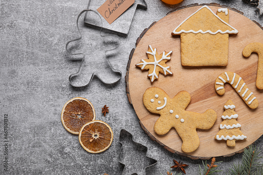 Board with Christmas gingerbread cookies and spices on grey background Board with Christmas gingerbread cookies and spices on grey background