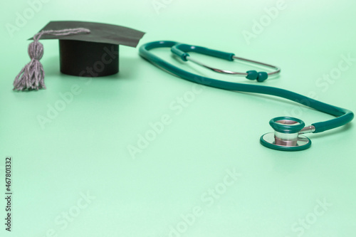 Medical education. Green stethoscope and graduate hat. Medical concept on mint background. graduate.