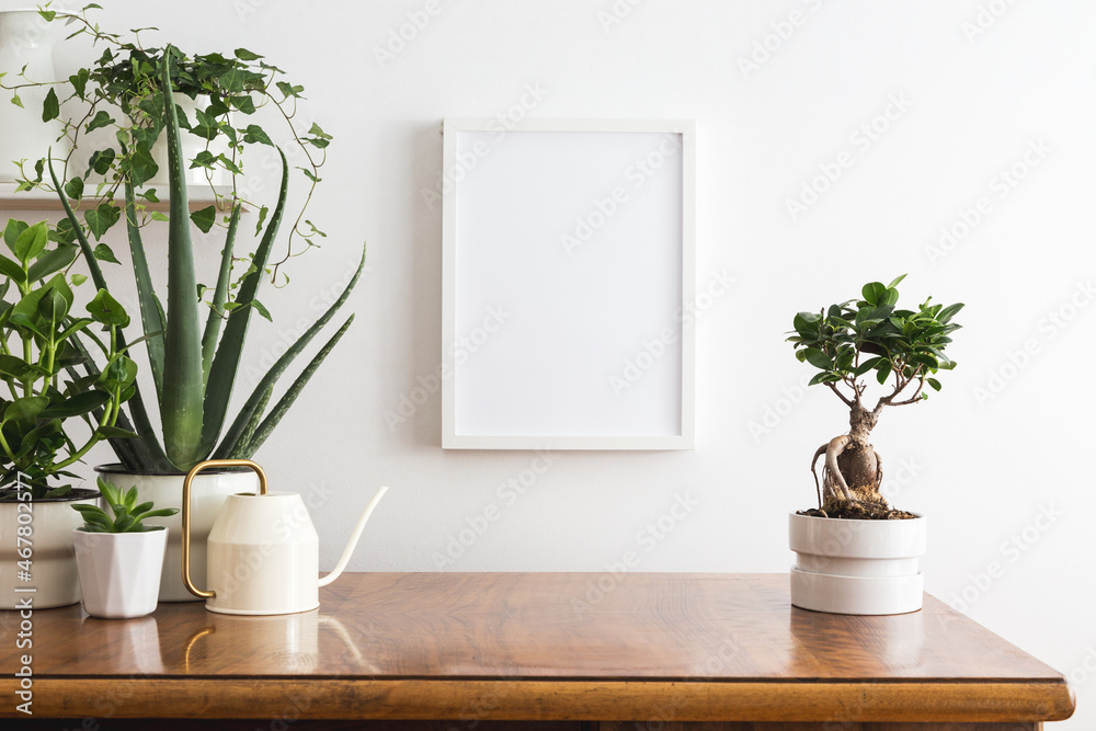 Wall with blank picture frame poster and desk objects, plants and bonsai tree on a white background..	
