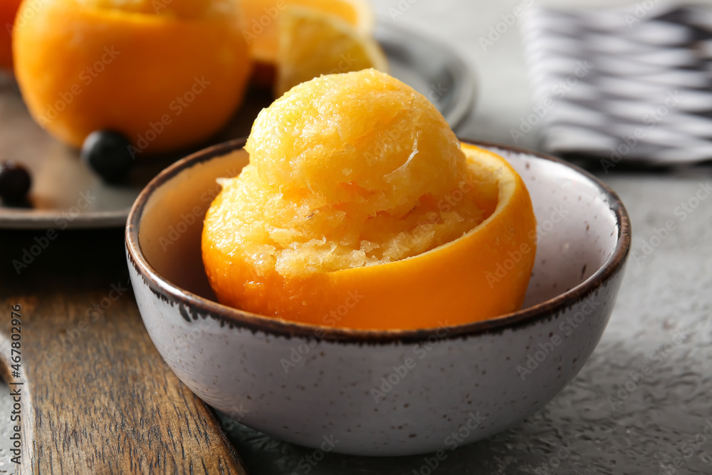 Bowl with tasty ice creams in orange peels on grey background Bowl with tasty ice creams in orange peels on grey background
