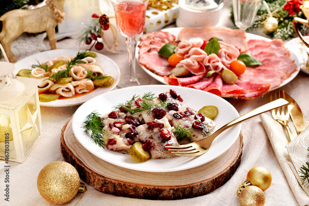 Sliced herrings with cranberry and with pickles Platter with sliced ham and cured meats for Christmas