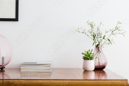 Table with paper magazines desk objects, and vase with bunch of spring flowers. a white background.. 