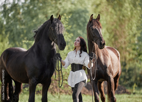 Beautiful long-haired girl on the lawn with two horses