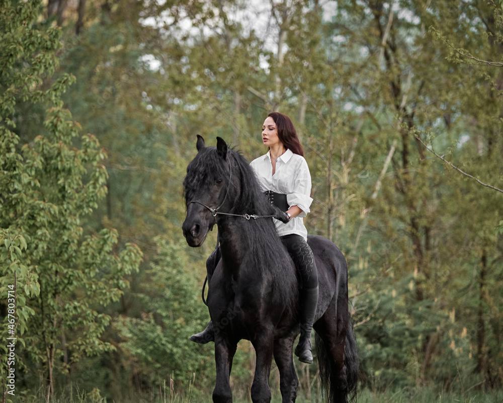 Beautiful long-haired girl riding a Friesian horse Beautiful long-haired girl riding a Friesian horse