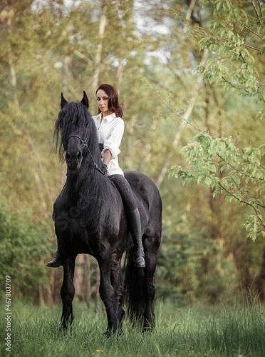Beautiful long-haired girl riding a Friesian horse © Елизавета Мяловская
