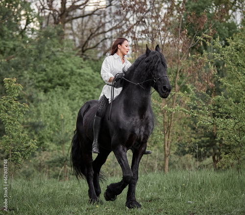 Beautiful long-haired girl riding a Friesian horse © Елизавета Мяловская