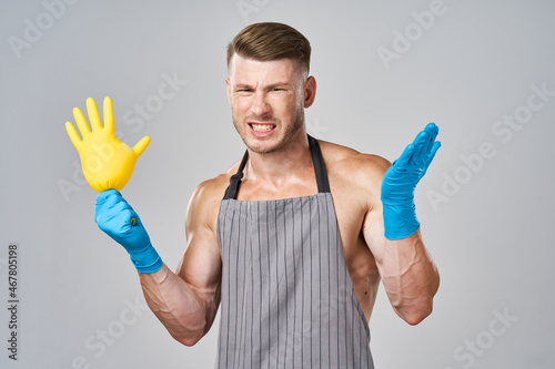 pumped up man in apron rubber gloves cleaning housework