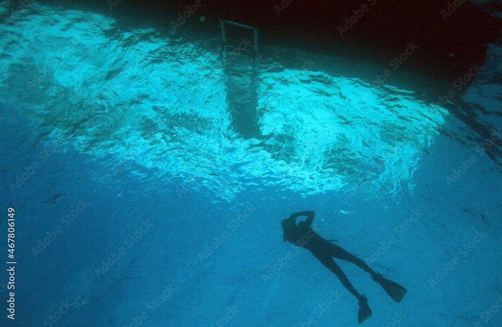  A Hawaiian Tropical Scuba Diver Woman Floating next to her Dive Boat Between Dive and Snorkeling with the Boat Reflecting in the Water