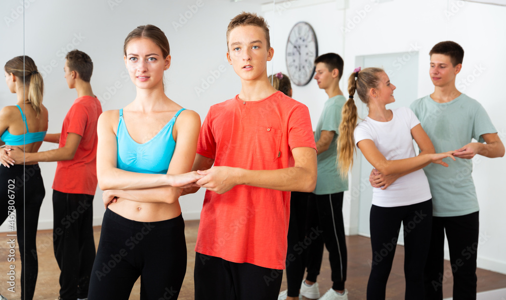 Fototapeta premium Teens in pairs learning to dance waltz with young female choreographer in modern studio ..