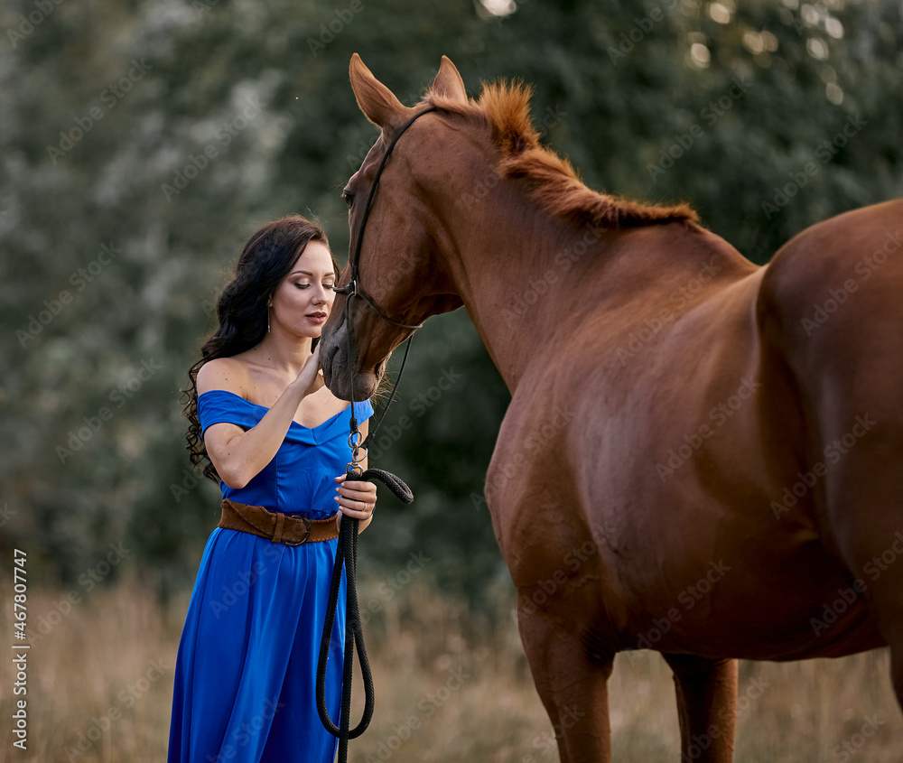 Obraz premium Beautiful long-haired girl in a blue dress with a red horse