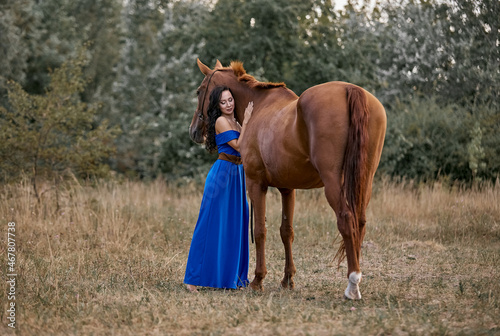 Beautiful long-haired girl in a blue dress with a red horse