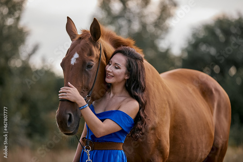 Beautiful long-haired girl in a blue dress with a red horse © Елизавета Мяловская