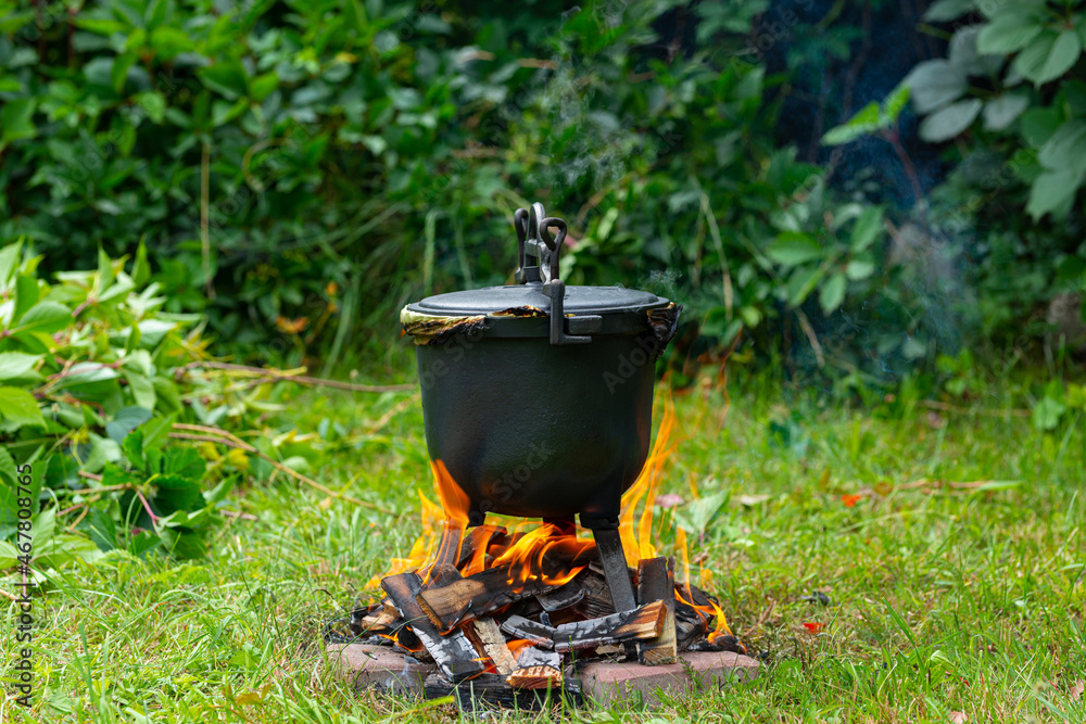 Preparing potatoes in a cast iron pot. Potato dish stewed on a fire, garden and outdoor recreation. Cooking on fire. Preparing potatoes in a cast iron pot. Potato dish stewed on a fire, garden and outdoor recreation. Cooking on fire.
