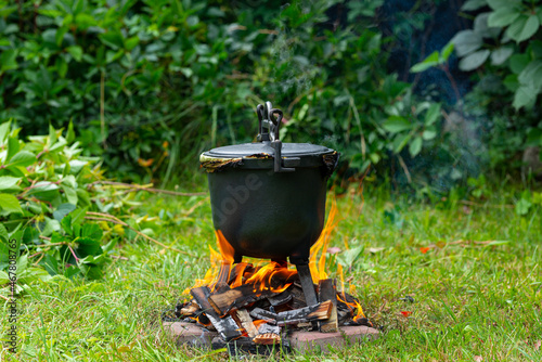 Preparing potatoes in a cast iron pot. Potato dish stewed on a fire, garden and outdoor recreation. Cooking on fire.