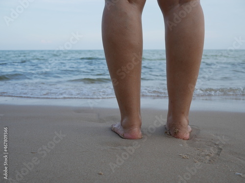 closeup of female legs standing on the sea beach.