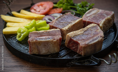 BEEF CUT INTO PIECES, WITH VEGETABLES SUCH AS TOMATO, ONION, PARSLEY, PEPPERS AND POTATOES, ON GRILL, READY TO BRING TO THE FIRE