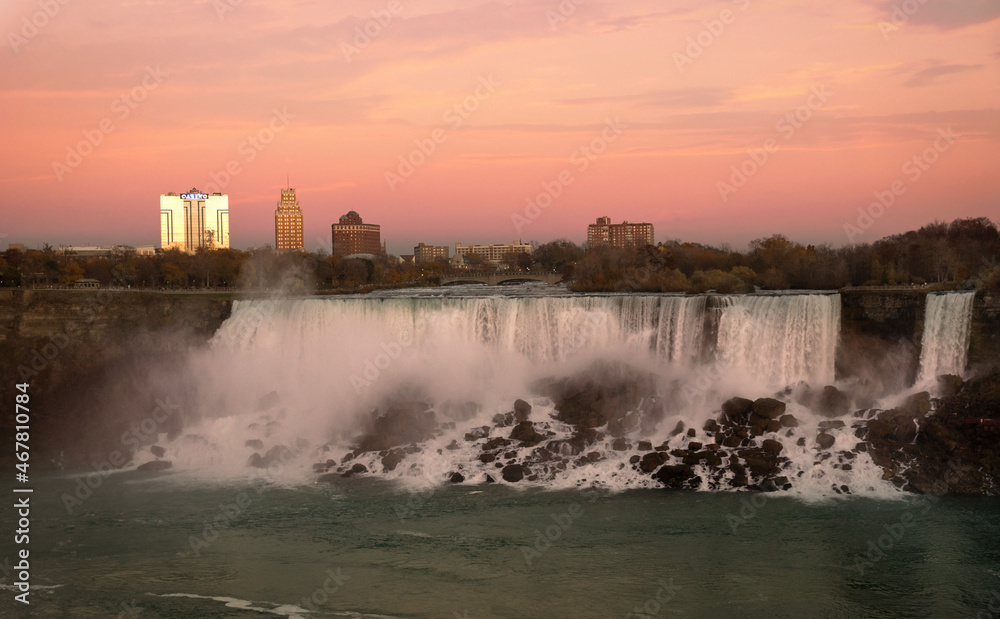 Sunset view of American Niagara Falls waterfall in front of spectacular sunset sky. American Falls is the second-largest of three Niagara waterfalls on the Niagara River along the Canada - U.S. border Sunset view of American Niagara Falls waterfall in front of spectacular sunset sky. American Falls is the second-largest of three Niagara waterfalls on the Niagara River along the Canada - U.S. border