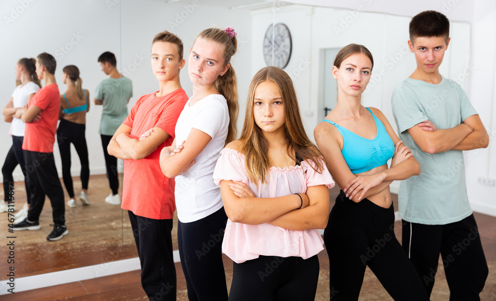 Fototapeta premium Cheerful teenage boys and girls having fun in choreography class, posing with female trainer..