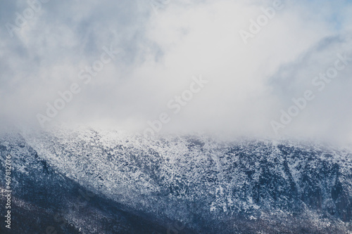 Snow on the mountain tops and clouds rolling over the thick vegetation shot in Tasmania, Australia