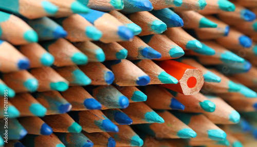 Photos A single orange colored pencil pointing in the opposite direction to the large quantity of sharp blue pencils