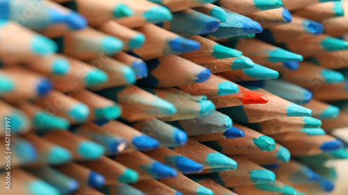 Foto A single sharp orange colored pencil pointing in the opposite direction to the blue pencils