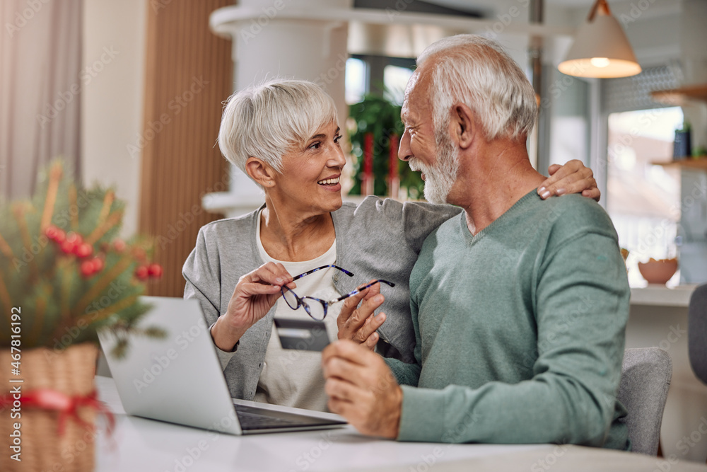 an embracing elderly couple shopping online for Christmas an embracing elderly couple shopping online for Christmas
