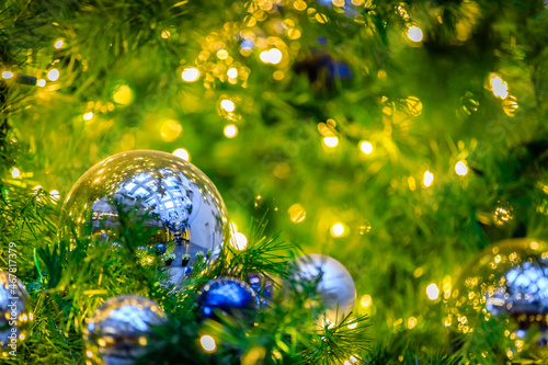 Warm green with blue and silver reflective Christmas ornaments lower left in a tree