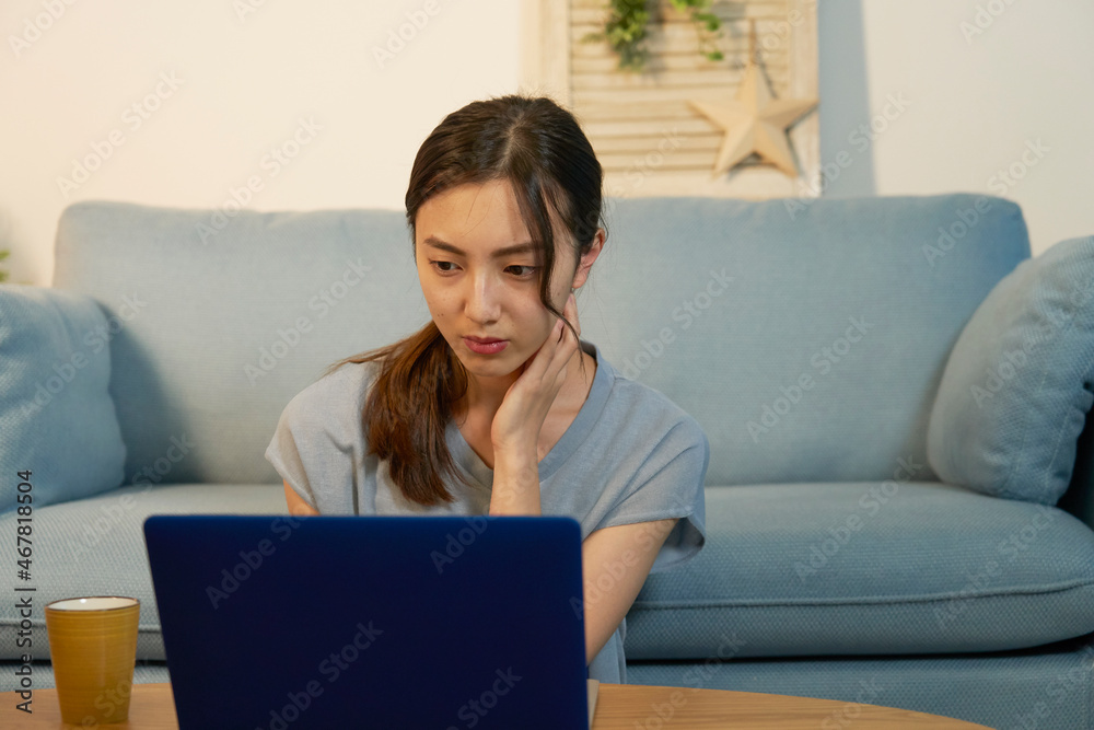 女性　パソコン　悩む　リビング　夜