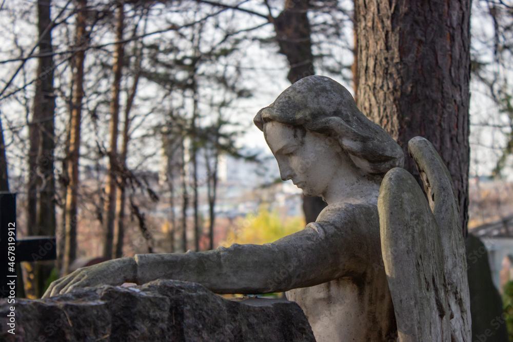 Sculpture of an angel made of stone on a grave in a cemetery