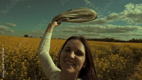 Beautiful woman with wind fluttering scarf in the rapeseed field. Woman freedom. Women rights.