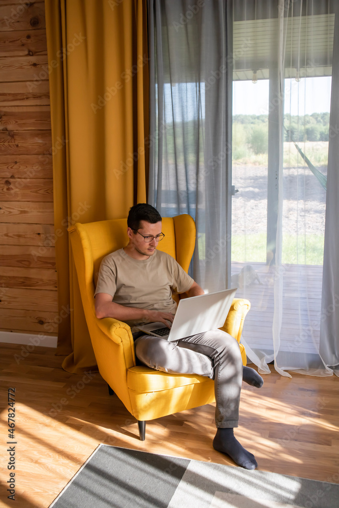 Comfortable place for working at home. A man is working in a big yellow armchair