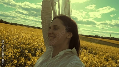 Beautiful woman with wind fluttering scarf in the rapeseed field. Woman freedom. Women rights.