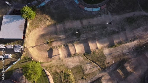 Ariel view of one person cycling on dirt racing track with his BMX bicycle at sunset. photo