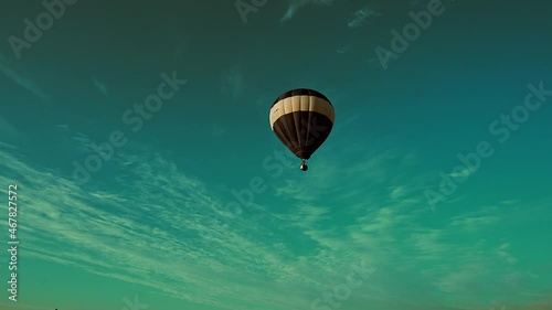 Hot air balloon flying overhead on morning sky background. Ballooning.