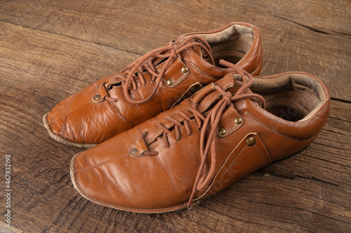 Mens brown old shoes on a dark wooden background.