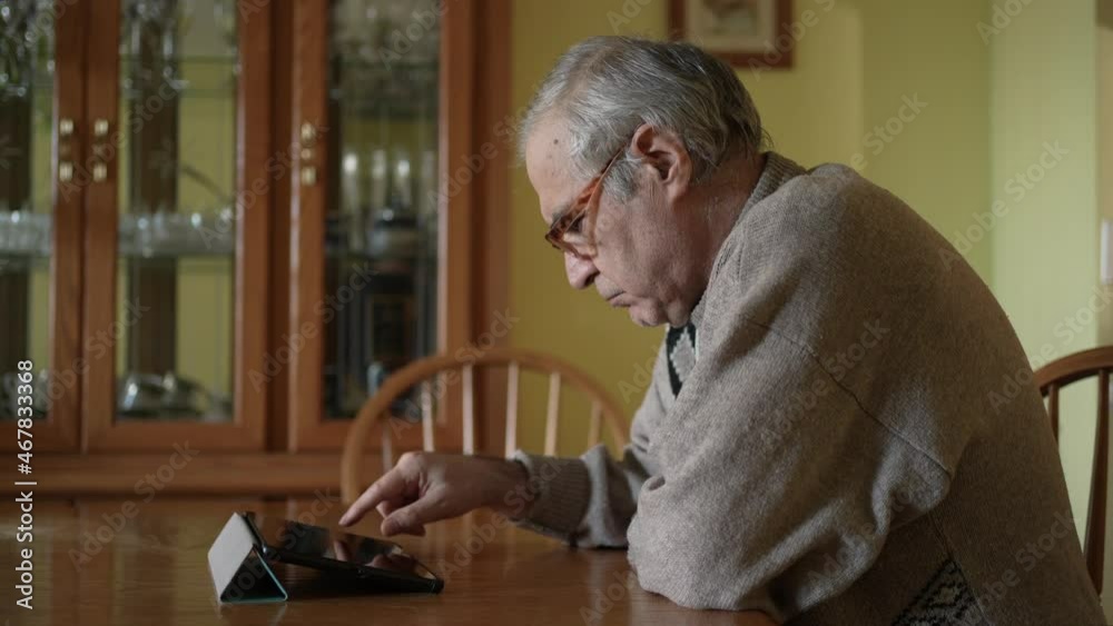 Senior Old Men Sitting at a Table and Using a Tablet Computer Senior Old Men Sitting at a Table and Using a Tablet Computer