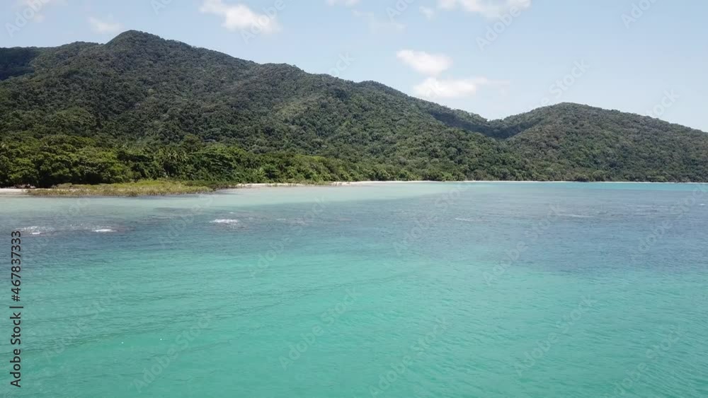 Low Drone aerial slow spin over tropical blue ocean reefs and Daintree rainforest