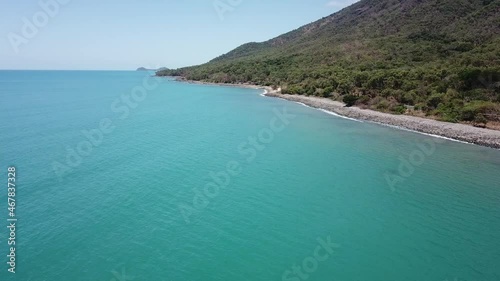 Drone aerial move forward and up over tropical blue water and mountain photo