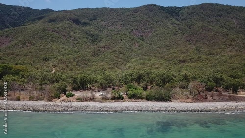 Drone moving up and pan down over tropical beach and mountainside photo