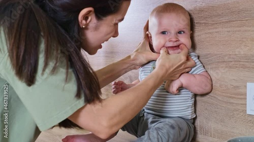 Mother rescuing child from choke with big piece of food. Infant swallowing fruit, gulp. Dangerous situation on the kitchen with baby eating vegetable