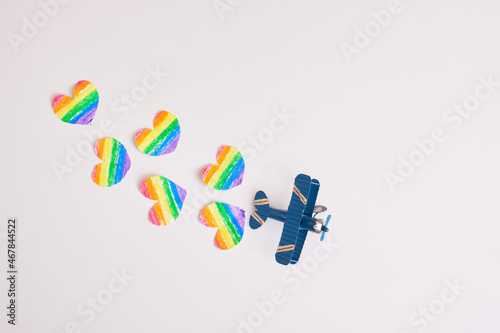 Fototapeta Naklejka Na Ścianę i Meble -  toy airplane and paper drawn cut out hearts rainbow colors on gray background