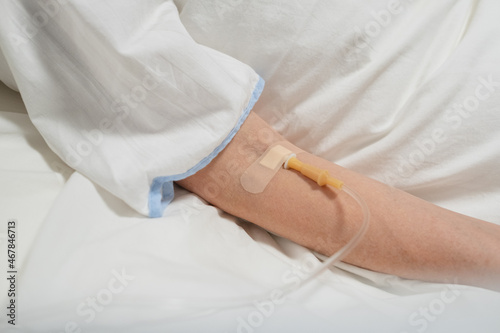 Close-up of patient lying on the bed under a drip in hospital ward