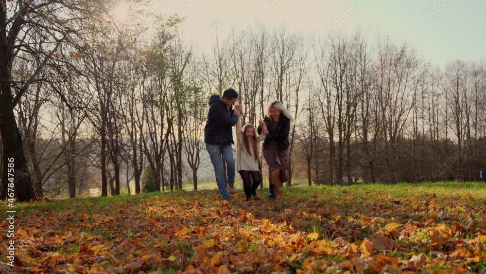 Full family hugging in autumn park. Three persons having fun at nature outdoors. Man and two girls running throw woods. People smile and laugh. Togetherness of different generations Full family hugging in autumn park. Three persons having fun at nature outdoors. Man and two girls running throw woods. People smile and laugh. Togetherness of different generations