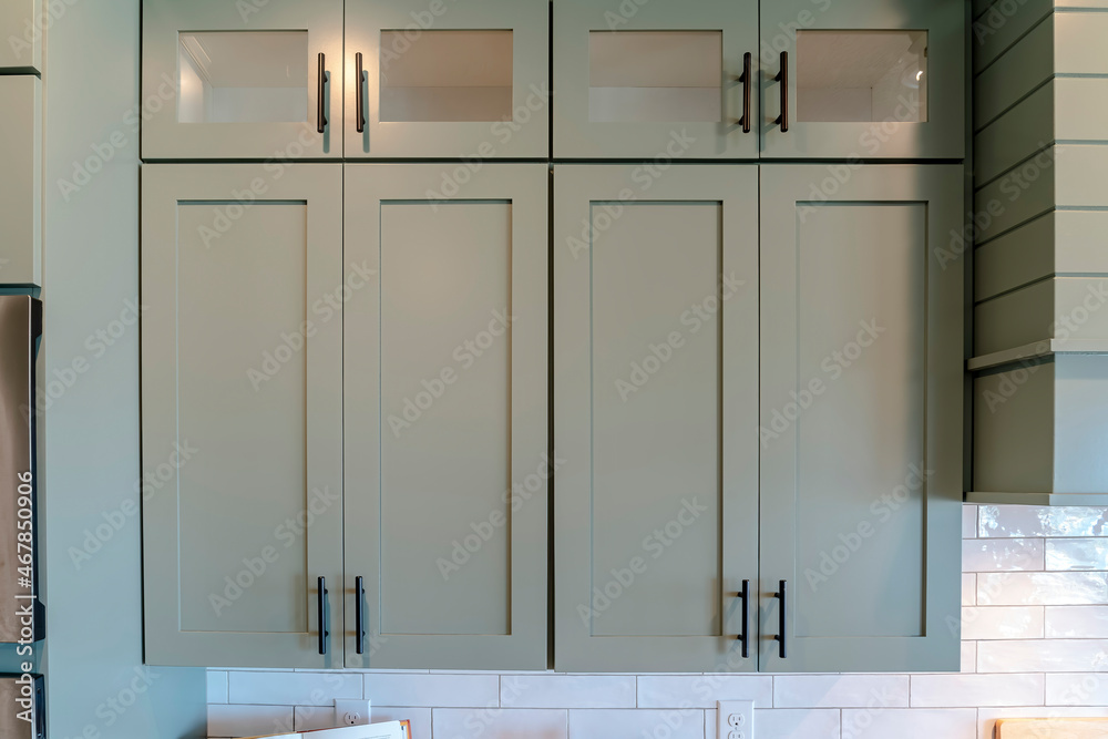 Wooden kitchen hanging cabinets with glass panes against white tile wall Wooden kitchen hanging cabinets with glass panes against white tile wall