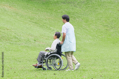 介護士と車椅子に乗る高齢者 屋外