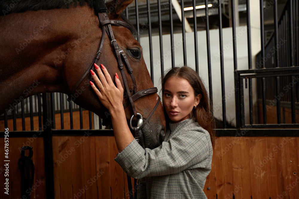 Portrait of smiling female jockey standing by horse in stable Portrait of smiling female jockey standing by horse in stable