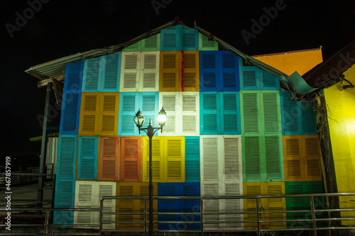 Old wooden house wall painted with many colors There is a lamp post in front. exterior decoration of the building