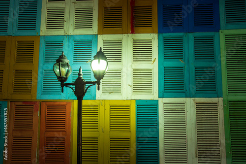 Old wooden house wall painted with many colors There is a lamp post in front. exterior decoration of the building